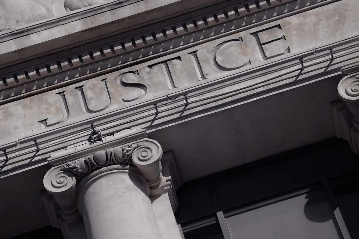 Close-up of a stone building facade with the word JUSTICE engraved in capital letters